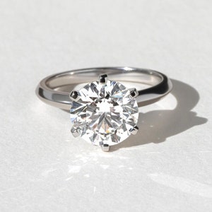 May include: A silver engagement ring with a large, round, clear diamond.