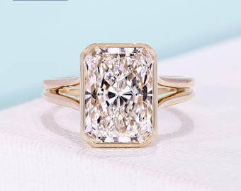 5.03ct radiant cut split shank engagement ring features a bezel set solitaire diamond, cathedral profile, and 14k yellow gold band