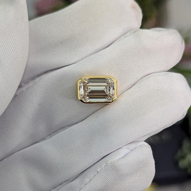 K&ouml;nnte beinhalten: Ein gro&szlig;er, klarer, smaragdgeschliffener Diamant, der in einer Goldfassung gefasst ist.