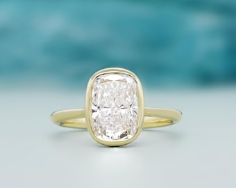 Könnte beinhalten: Ein Goldring mit einem großen, rechteckigen, im Kissenschliff facettierten, klaren Edelstein in einer glatten Zargenfassung. Die Ringschiene ist schmal und poliert aus Gelbgold gefertigt und betont die facettierte Oberfläche des Steins.