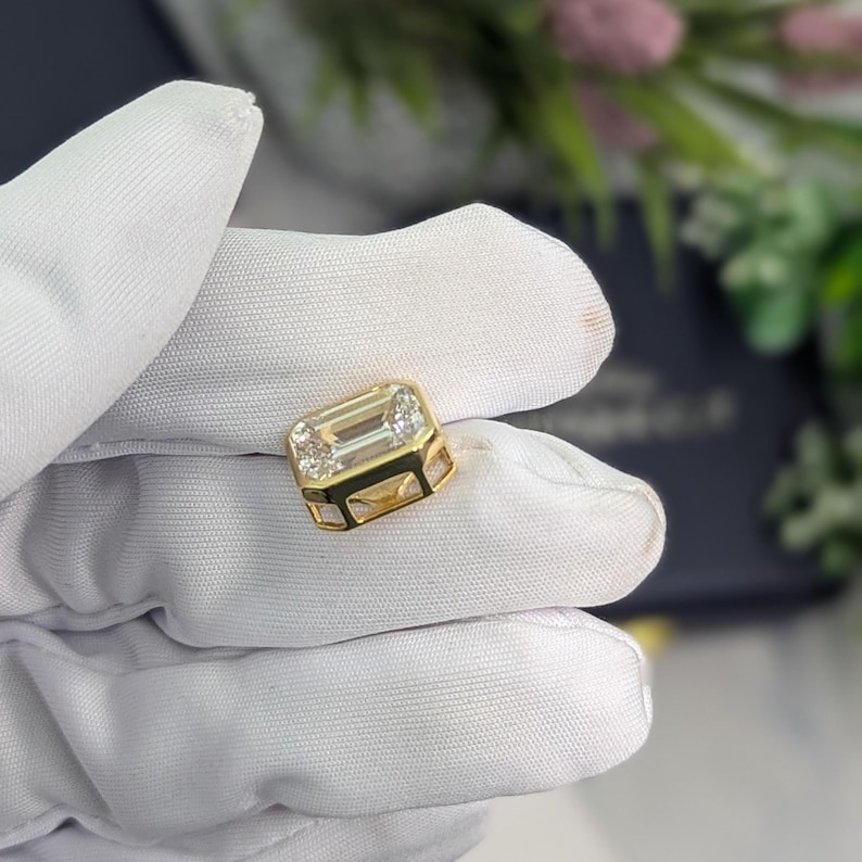 K&ouml;nnte beinhalten: Ein goldener Ring mit einem gro&szlig;en, klaren Smaragdschliff-Edelstein.