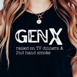 May include: A black t-shirt with white text that reads "GENX raised on TV dinners & 2nd hand smoke".