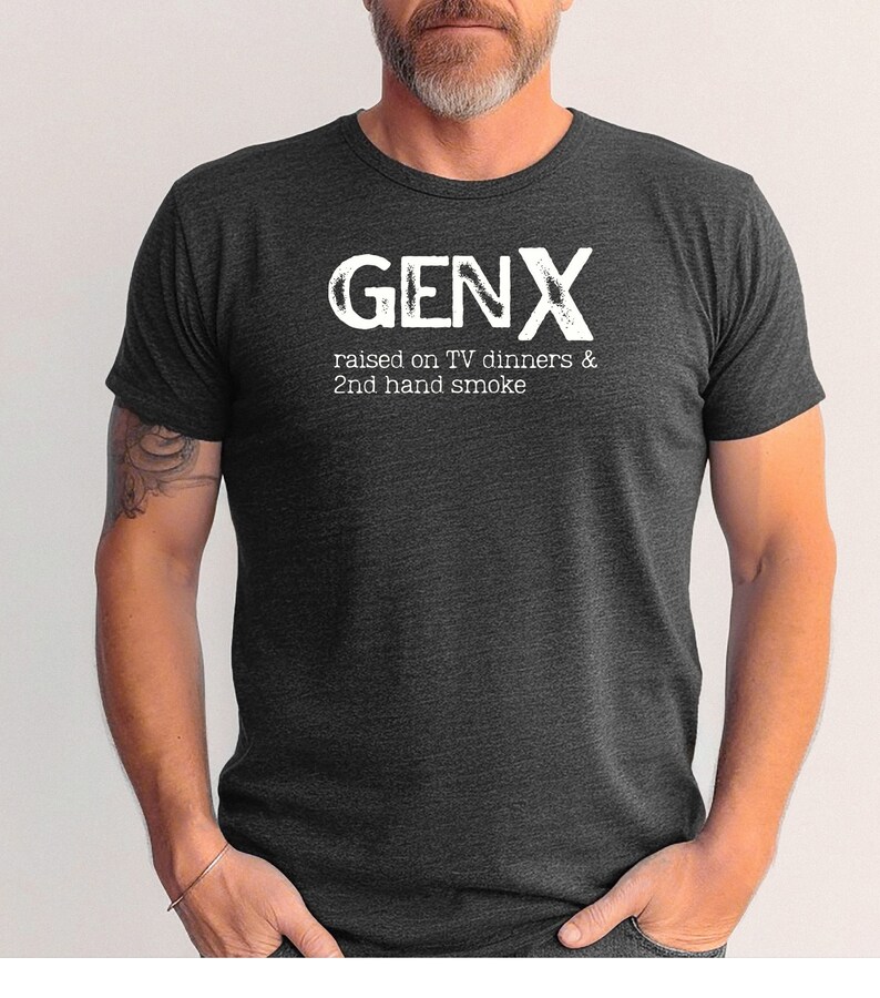 May include: A dark gray t-shirt with the text "GENX" in white, and the phrase "raised on TV dinners & 2nd hand smoke" in white below it.