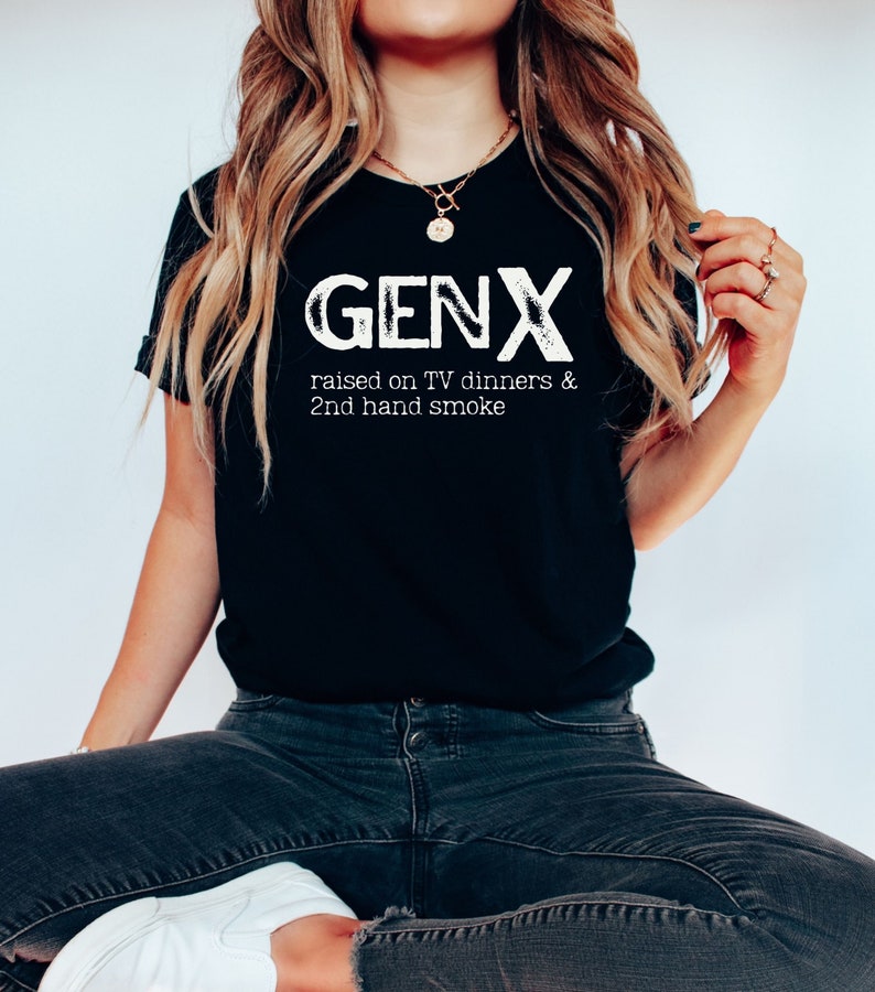 May include: A black t-shirt with white text that reads "GENX raised on TV dinners & 2nd hand smoke".