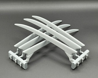 May include: A set of four silver-colored claws with a textured surface. The claws are attached to a base with a series of small, rectangular holes.