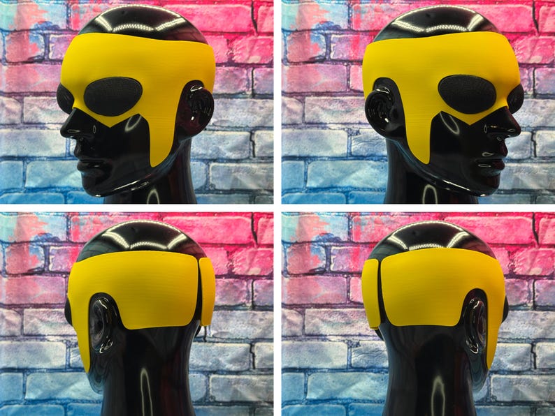 May include: A bright yellow superhero-style mask featuring a smooth, contoured design that covers the forehead and temples, with large oval cutouts for the eyes. The mask is displayed on a glossy black mannequin head from multiple angles.