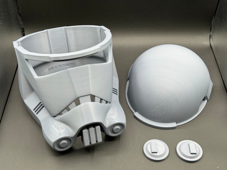 May include: A 3D printed white plastic helmet with a dome, faceplate, and two small round pieces. The helmet has the text "GALACTICARMORY" printed on the front.