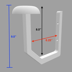 Może przedstawiać: Biały, ścienny wieszak na kapelusze w kształcie litery U. Wieszak ma 22,86 cm wysokości, 20,32 cm wysokości i 15,88 cm szerokości. Na g&oacute;rze znajduje się zaokrąglona p&oacute;łka. Wieszak ma dwa otwory do montażu.