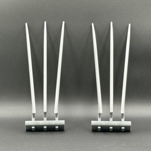 May include: Two sets of three silver-colored claws with a black base. The claws are long and thin, and they are arranged in a fan shape.
