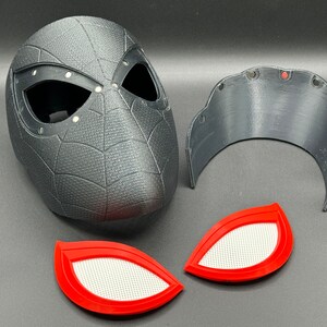 Puede incluir: Una m&aacute;scara de Spider-Man impresa en 3D de color negro y gris con un patr&oacute;n de telara&ntilde;a y lentes de ojos rojos. La m&aacute;scara est&aacute; en tres piezas, incluyendo una pieza de frente separada y dos piezas de ojos rojos.