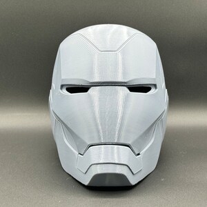 Puede incluir: Un casco de Iron Man gris impreso en 3D. El casco tiene un dise&ntilde;o detallado con una superficie texturizada.