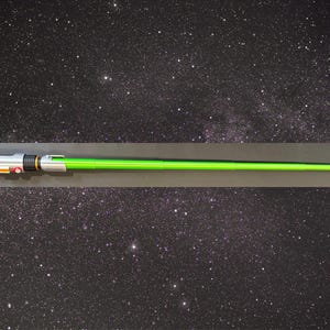 May include: A green lightsaber prop with a silver and black handle. The lightsaber is displayed against a starry background, suggesting a space or sci-fi theme. The handle has orange and red buttons.