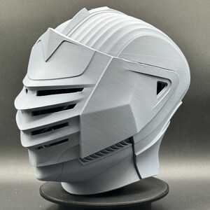 Puede incluir: Un casco blanco impreso en 3D con una visera y un dise&ntilde;o detallado. El casco tiene una superficie texturizada y parece estar hecho de pl&aacute;stico.