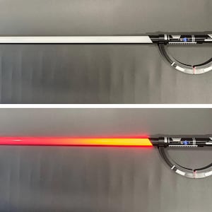 May include: A black and silver lightsaber with a white blade, and a second image with a red and orange blade. The hilt features detailed silver accents and a curved guard. The lightsaber is a prop or toy.