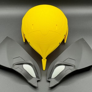 May include: A yellow helmet with two black side pieces. The helmet has a textured surface and the side pieces have a smooth surface.