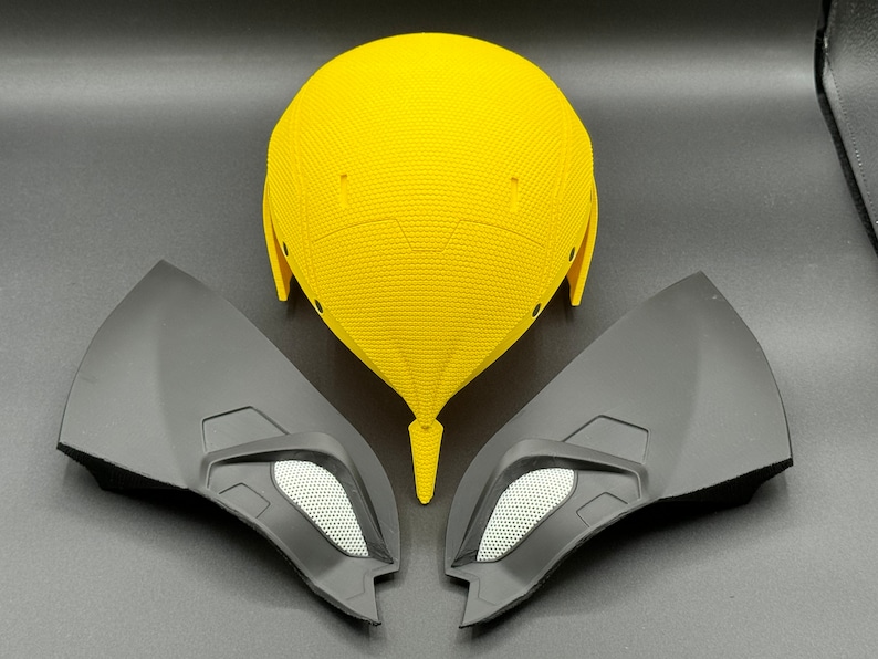 May include: A yellow helmet with two black side pieces. The helmet has a textured surface and the side pieces have a smooth surface.