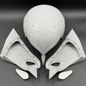 Puede incluir: Un conjunto de cinco piezas de casco de pl&aacute;stico gris, que incluye una pieza principal de casco con un dise&ntilde;o circular, dos piezas laterales y dos piezas m&aacute;s peque&ntilde;as. Las piezas est&aacute;n dispuestas sobre una superficie gris.