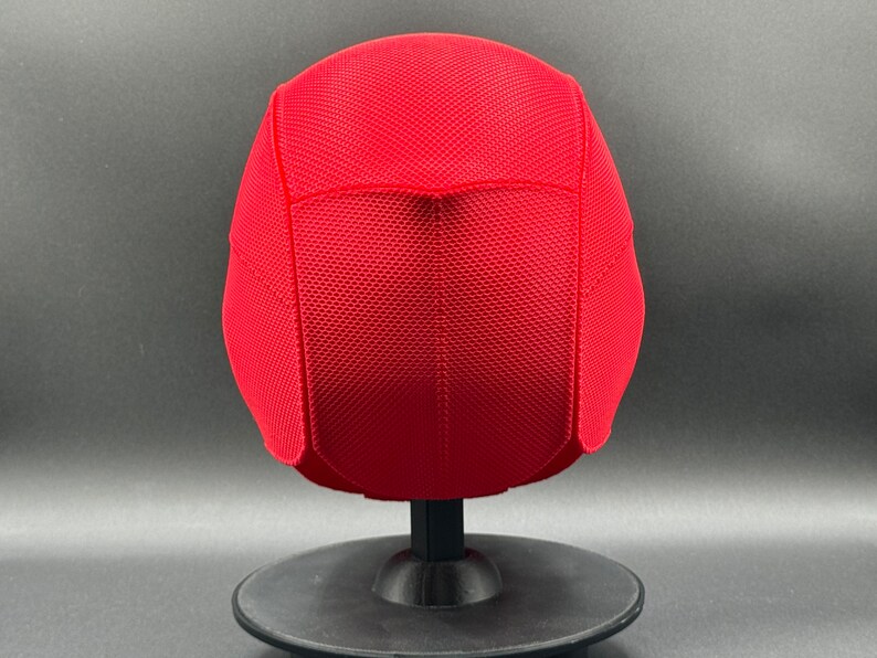 May include: Red mesh baseball cap with a curved brim. The cap is on a black display stand.