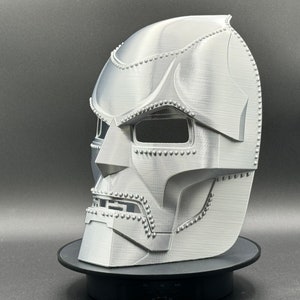 May include: A 3D printed silver mask of Doctor Doom, a fictional supervillain from Marvel Comics. The mask is detailed with rivets and has a textured surface.