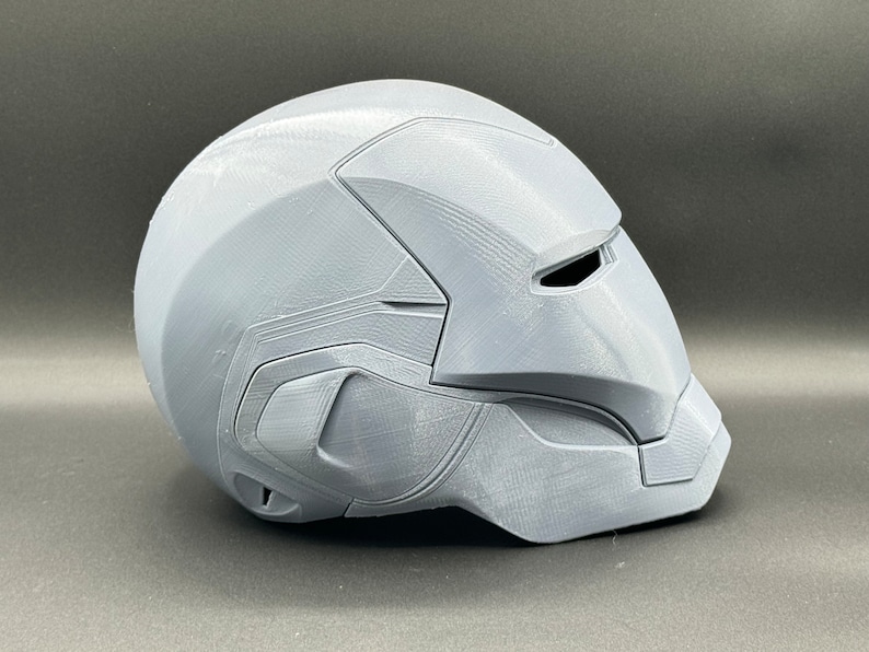 Puede incluir: Un casco gris impreso en 3D con una superficie texturizada y una visera.
