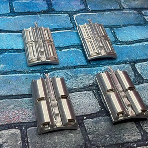 以下が含まれることがあります： 青とグレーのレンガ模様の表面に配置された、詳細な建築デザインの4つの銀色の長方形のオブジェクト。 各ピースは、中央の垂直要素と湾曲したベースを備えています。