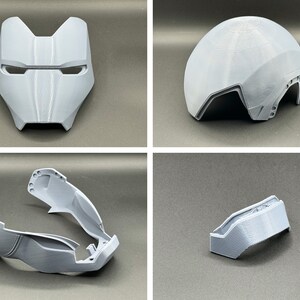 Puede incluir: Un casco de pl&aacute;stico gris impreso en 3D con una m&aacute;scara facial, una pieza superior y dos piezas laterales. El casco est&aacute; dise&ntilde;ado para parecer un casco futurista o de ciencia ficci&oacute;n.