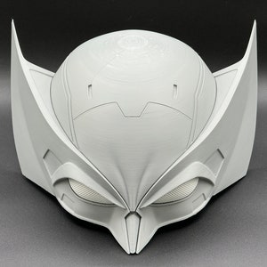 Puede incluir: Una m&aacute;scara blanca impresa en 3D con un dise&ntilde;o detallado. La m&aacute;scara tiene una barbilla puntiaguda y grandes agujeros para los ojos angulares.