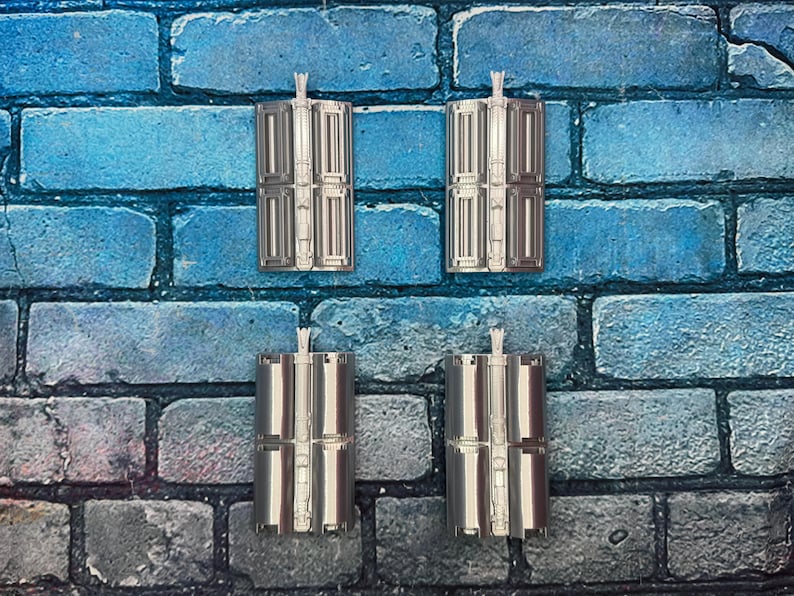 以下が含まれることがあります： 詳細なデザインの銀色の長方形のオブジェクトが4つ、グリッド状に配置されています。各オブジェクトの上部には小さな垂直のハンドルが付いています。オブジェクトは、青とグレーのレンガの壁を背景にしています。