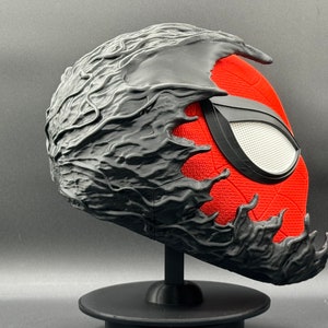 Puede incluir: Una m&aacute;scara impresa en 3D de color negro y rojo con un dise&ntilde;o org&aacute;nico texturizado negro que cubre la mitad superior de la m&aacute;scara. La mitad inferior de la m&aacute;scara es roja con un dise&ntilde;o de Spider-Man negro.