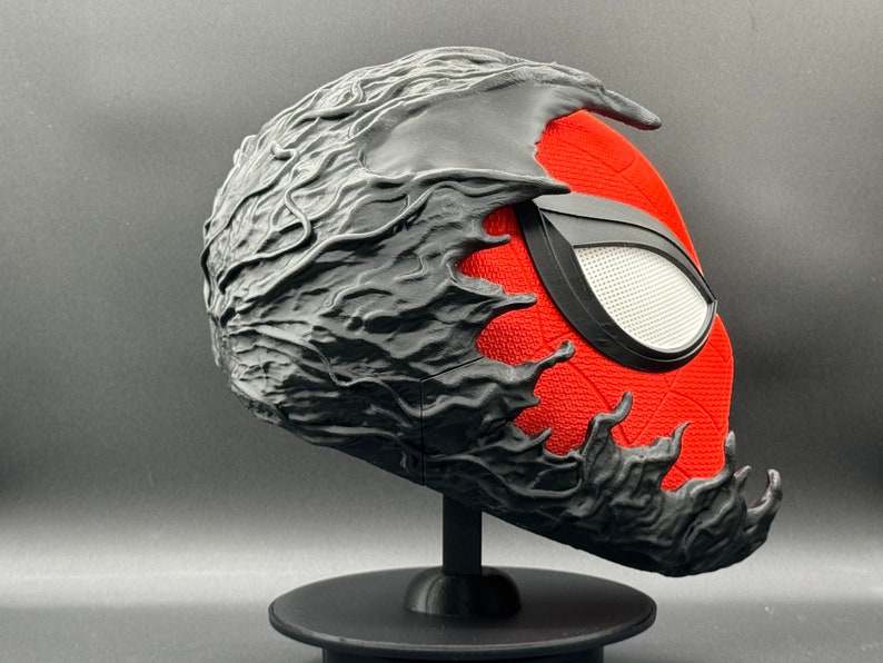 Puede incluir: Una m&aacute;scara impresa en 3D de color negro y rojo con un dise&ntilde;o org&aacute;nico texturizado negro que cubre la mitad superior de la m&aacute;scara. La mitad inferior de la m&aacute;scara es roja con un dise&ntilde;o de Spider-Man negro.