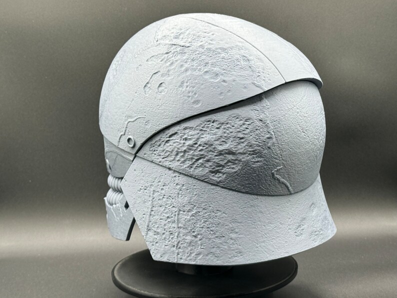 May include: A white, textured helmet with a raised design. The helmet is made of a hard plastic material and has a visor that can be raised or lowered.