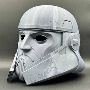 May include: A gray 3D printed helmet with a textured surface and a detailed design. The helmet has a visor and a chin guard.