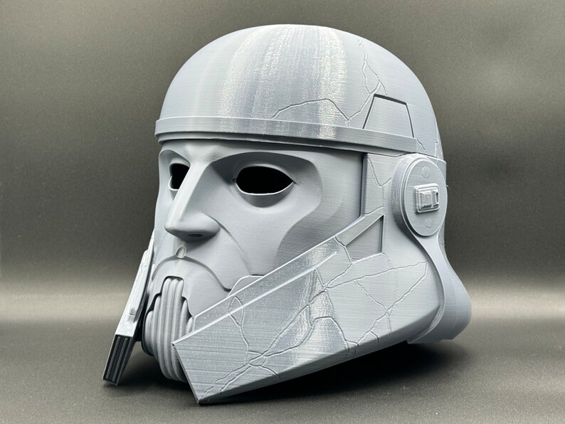 May include: A gray 3D printed helmet with a textured surface and a detailed design. The helmet has a visor and a chin guard.