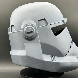 May include: A white plastic helmet with a visor and a textured surface. The helmet is designed to resemble a Star Wars character.