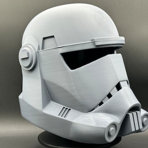 May include: A white plastic 3D printed helmet with a visor and a detailed design. The helmet is a replica of a Star Wars character.