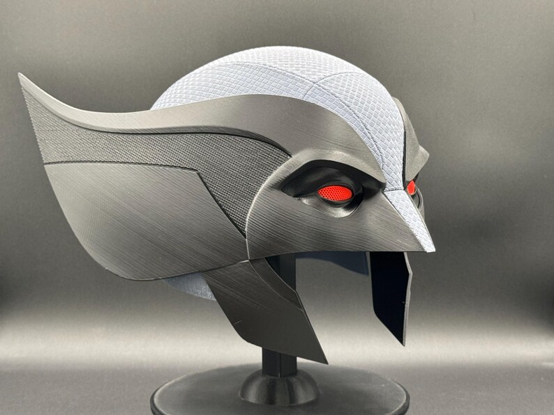 May include: A black and gray helmet with red eyes. The helmet has a textured surface and a sharp, angular design.