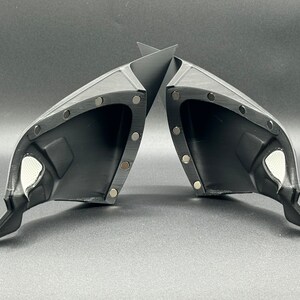May include: A pair of black plastic car side view mirrors with a textured surface and multiple small silver dots around the edges.
