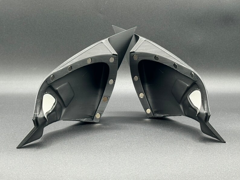 May include: A pair of black plastic car side view mirrors with a textured surface and multiple small silver dots around the edges.
