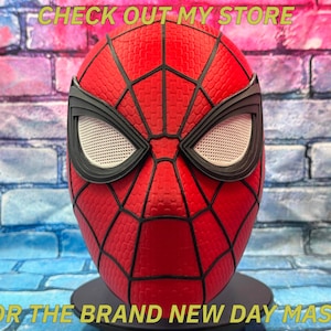 以下が含まれることがあります： 黒いクモの巣と目の詳細が施された赤いスパイダーマンマスク。マスクはテクスチャ加工された表面で、黒いスタンドに展示されています。上部のテキストは「CHECK OUT MY STORE」、下部のテキストは「FOR THE BRAND NEW DAY MASK！」です。