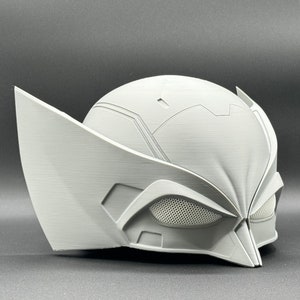 Puede incluir: Un casco blanco de pl&aacute;stico impreso en 3D con un dise&ntilde;o detallado. El casco tiene una visera con un patr&oacute;n de malla y una barbilla puntiaguda.