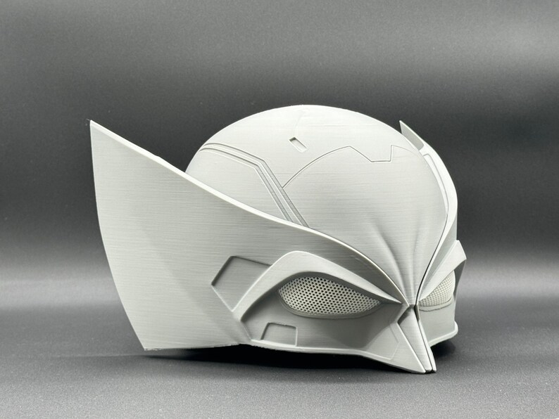 Puede incluir: Un casco blanco de pl&aacute;stico impreso en 3D con un dise&ntilde;o detallado. El casco tiene una visera con un patr&oacute;n de malla y una barbilla puntiaguda.