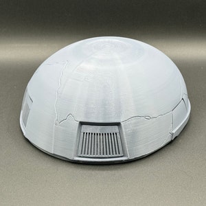 May include: A gray, dome-shaped object with a textured surface and a series of rectangular vents on the bottom.