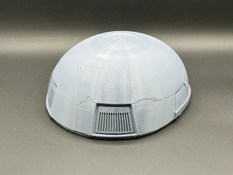 May include: A gray, dome-shaped object with a textured surface and a series of rectangular vents on the bottom.