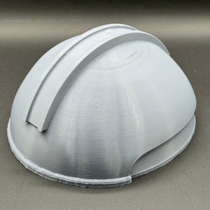 Puede incluir: Un casco gris impreso en 3D con una cresta elevada en la parte superior.