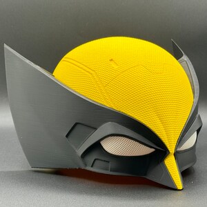 May include: A yellow and black plastic mask with a textured surface. The mask has a raised design on the forehead and a black eye mask with a white mesh.