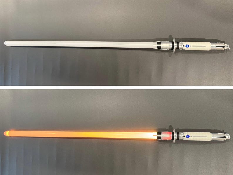 May include: A silver and white lightsaber with a glowing orange blade. The hilt features silver and black accents with blue and red buttons. The lightsaber is shown both on and off, with the blade illuminated in the on position.
