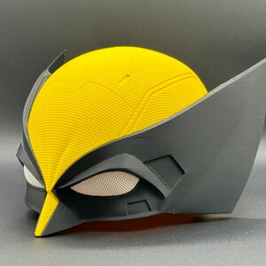 May include: A yellow and black plastic mask with a textured surface and a mesh eye covering. The mask is designed to resemble a superhero character.