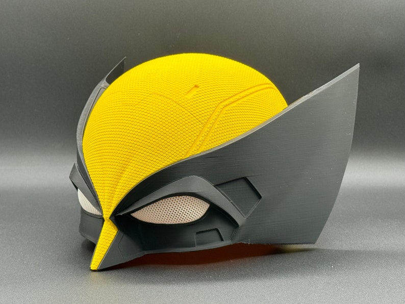 May include: A yellow and black plastic mask with a textured surface and a mesh eye covering. The mask is designed to resemble a superhero character.