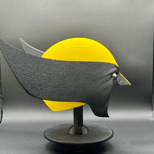 Puede incluir: Una m&aacute;scara de Wolverine impresa en 3D de color amarillo y negro sobre un soporte negro. La m&aacute;scara tiene una superficie texturizada y est&aacute; dise&ntilde;ada para parecerse al rostro del personaje.