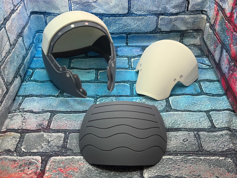 May include: Three-piece set of protective gear, including a helmet, elbow pad, and a chest protector. The helmet is white and gray, with a curved design. The elbow pad is white, and the chest protector is gray with a wavy pattern.